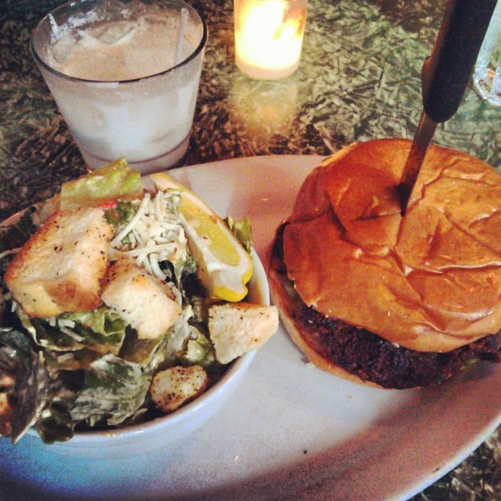 The veggie burger with a side of caesar salad and a coconut caipirinha cocktail.