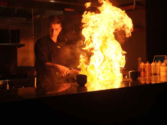 A chef lighting up the teppan grill.